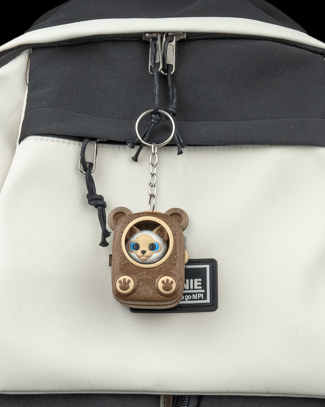 Cuddle Pack Siamese collectible keychain on a stylish backpack, perfect for cat lovers.
